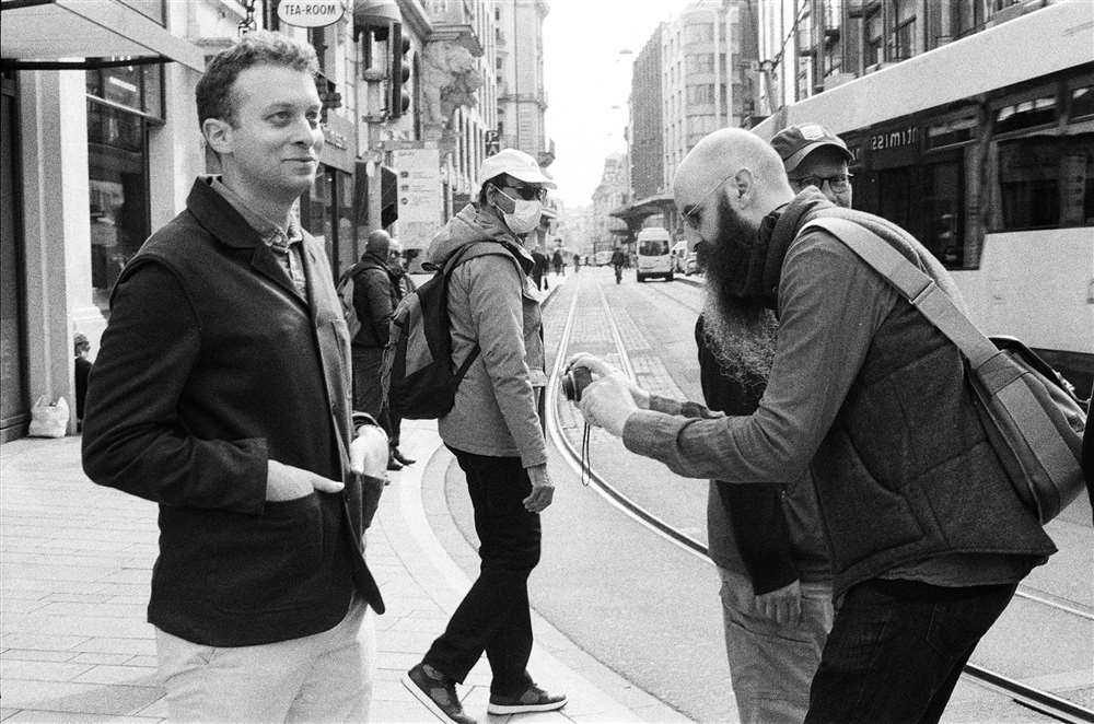 兩名男子在繁忙的街道一側拍下手腕照片。