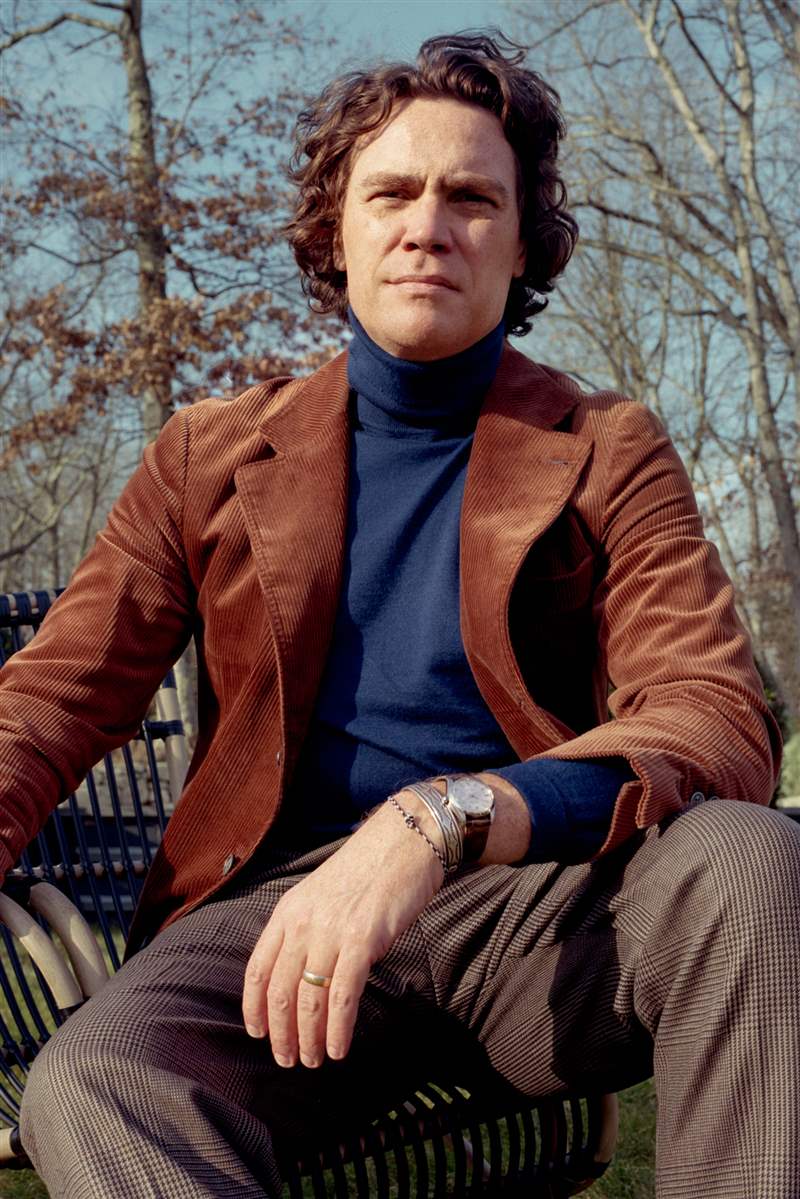 一個男人穿著西裝外套在外面擺姿勢，看著