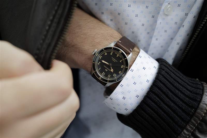 38 毫米尺寸的 Hamilton Khaki Pilot Pioneer 戴在手腕上，手伸進棕色皮夾克的口袋里。
